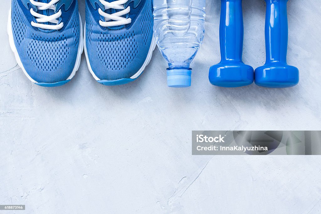 Zapatos deportivos laicos planos, botella de agua y mancuernas - Foto de stock de Ejercicio físico libre de derechos