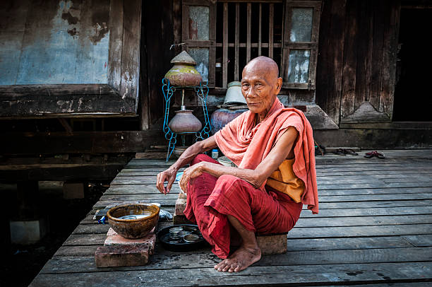 Old Burmese monk in Mandalay, Myanmar A Burmese monk in his 70s, sitting outside his monastery where he is washing dishes, in Mandalay, Myanmar mandalay photos stock pictures, royalty-free photos & images