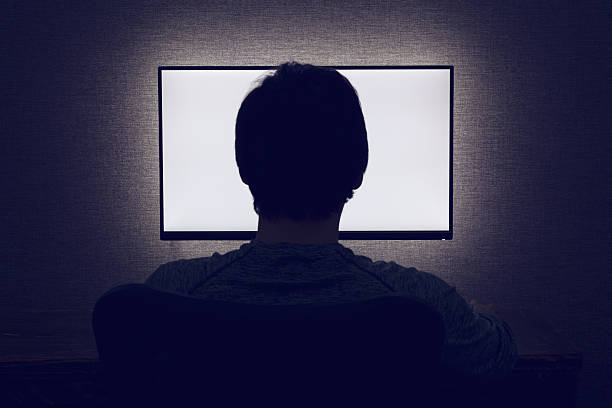 Man sits in front of a blank monitor in dark room