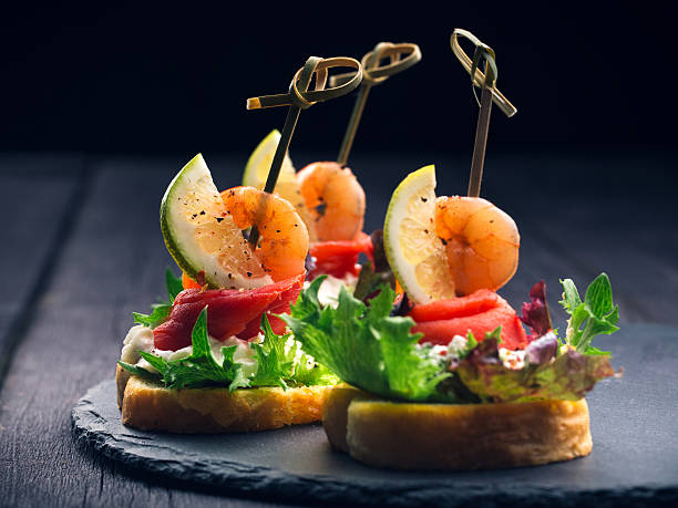 Toasted Canape with Shrimp and Salmon Toasted Canape with Shrimp and Salmon on dark background close-up canape stock pictures, royalty-free photos & images