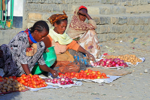 Mekele, Ethiopia-March 29, 2013: Tigrayan women sell vegetables -onions-potatoes-tomatoes- at their stall on the sidewalk of a street under the evening sun on March 29, 2013 in Mek'ele-Mekelle-Tigray region