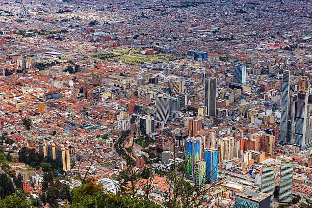 Bogota, Colombia - Looking at the downtown area of the Andean capital city of Bogota, Colombia in South America, from the mountain peak called Monserrate. Concrete towers, churches, plazas, roads and streets can all be seen. The red terracotta roof tiled buildings to the left of the image are located in La Candelaria, where the city was founded in 1538; it is the oldest part of the city. Located at about 8500 feet above mean sea level, with a population of almost 10 Million, Bogota is one of the largest cities in Latin America. The main square, Plaza Bloivar, with the parliament building, can be clearly seen - left of centre. To the right are the modern towers in the City. Image demonstrates the old and the new, in significant contrast. Photo shot in the morning sunlight.  Horizontal format.