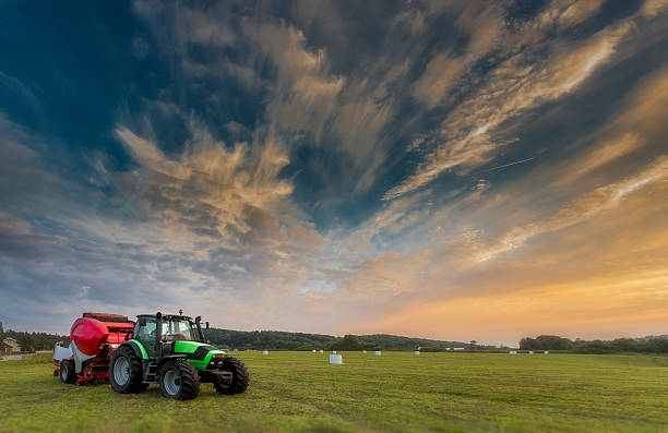 tracteur à la lumière du coucher du soleil avec des boules d’ensilage en arrière-plan - provender photos et images de collection