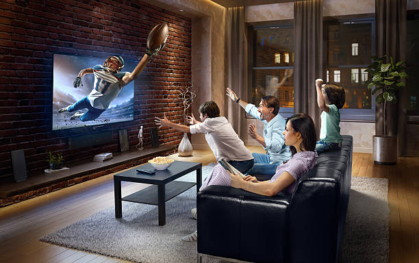 семья с детьми смотрит американский футбольный матч по телевизору - home interior entertainment sofa men стоковые фото и изображения