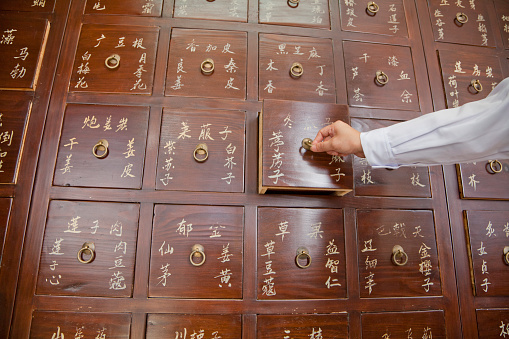 Doctor opening drawer of Chinese medicine cabinet