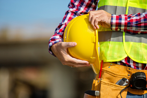 Joven trabajador de la construcción sosteniendo un casco amarillo photo