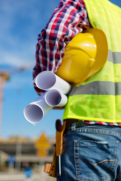istock Young construction worker holding blueprints and helmet 618948684
