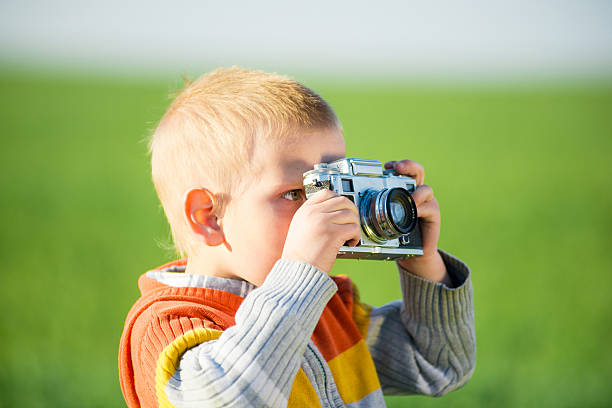 istock Little boy with an old camera shooting outdoor. 618956954
