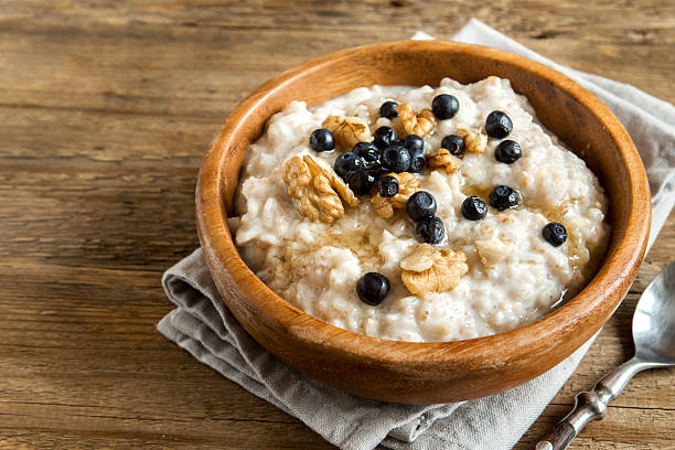 Oatmeal porridge Oatmeal porridge with walnuts, blueberries and honey in wooden bowl with copy space - healthy rustic breakfast porridge stock pictures, royalty-free photos & images