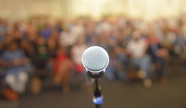 istock Empty microphone in front of a crown of people 618963236