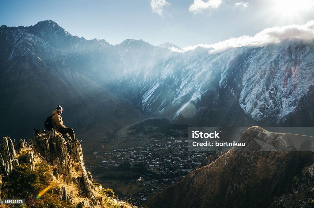 Routard assis sur le bord de la falaise et regarde la vallée du mont - Photo de Montagne libre de droits