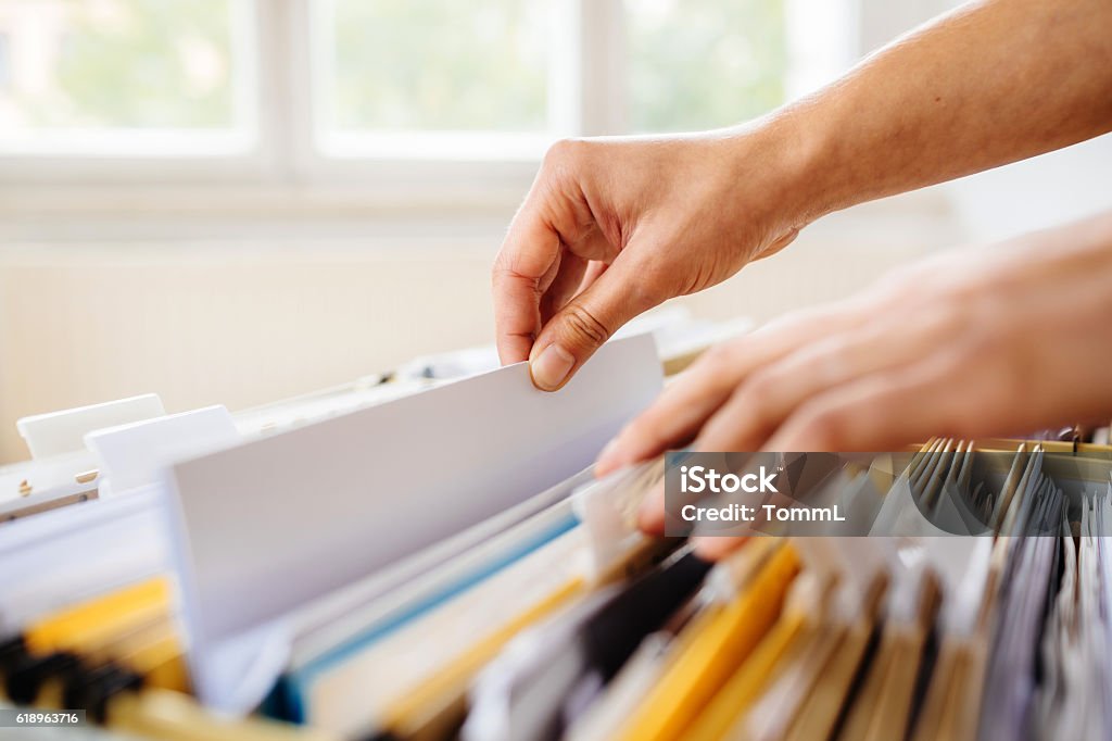 Filing In File Cabinet Close-up of hands searching in a file cabinet Document Stock Photo