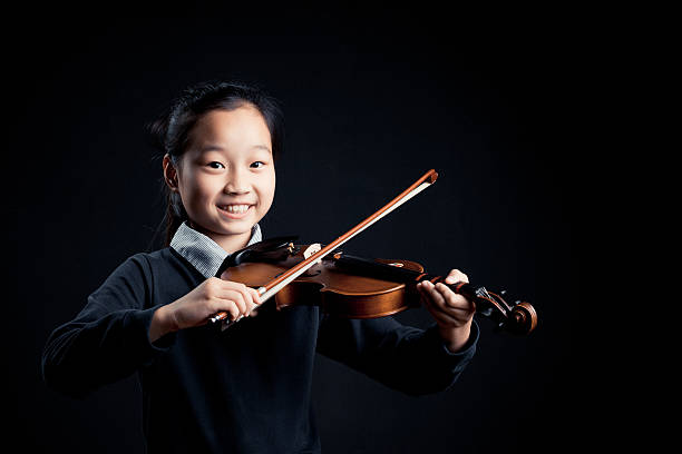 istock girl playing a Violin isolated over a black background 618963944