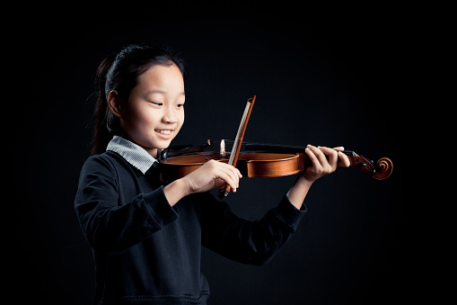 girl playing a Violin isolated over a black background
