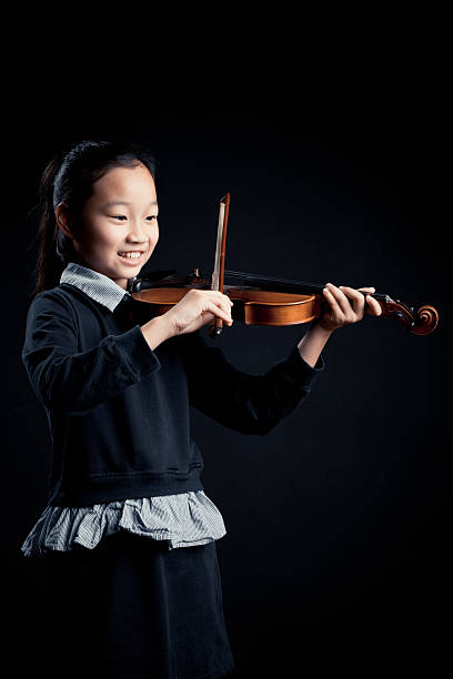 istock girl playing a Violin isolated over a black background 618965226