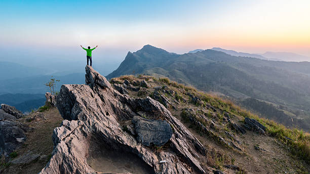 istock Winner man on peak of rocks mountain Hike at sunset 618968336