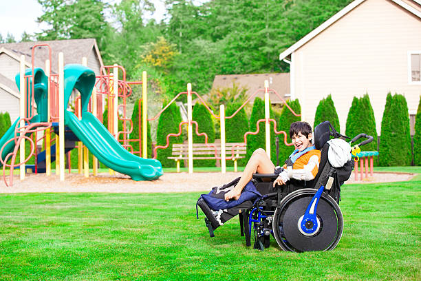 istock Smiling disabled boy in wheelchair sitting at a park 618968802