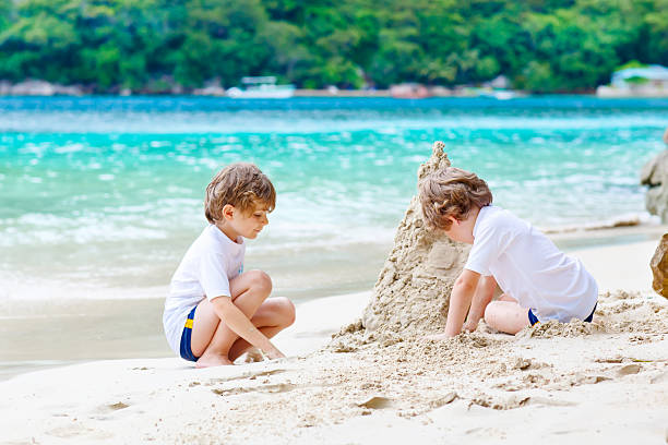 istock Two kid boys building sand castle on tropical beach 618968930