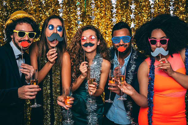 New Year's Eve Friends goofing around with fake moustaches and glasses on a New Year's Eve party. New Year’s Eve Outfit stock pictures, royalty-free photos & images