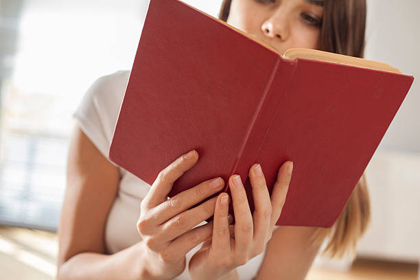 istock Young woman reading book in home 618970558