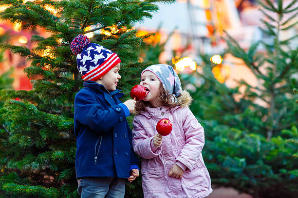 istock Two little kids eating crystalized apple on Christmas market 618972862