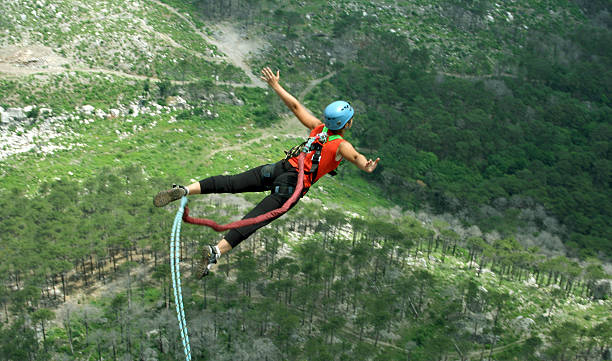 Jump rope. A woman jumps from a cliff into the abyss. bungee jumping stock pictures, royalty-free photos & images