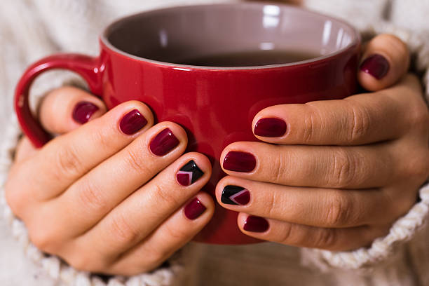 istock Woman with red manicure holding a red cup of tea 618975962