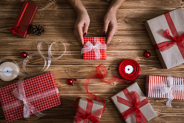 istock Female hands wrapping xmas gifts into paper and tying them 618976624