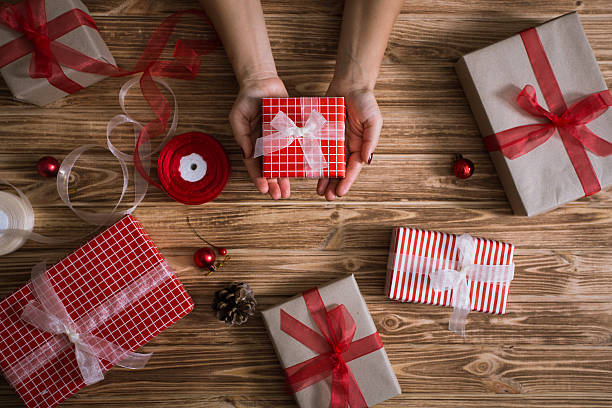 istock Female hands wrapping xmas gifts into paper and tying them 618976692