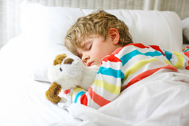 istock little blond kid boy in colorful nightwear clothes sleeping 618977544