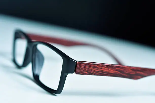 closeup of a pair of plastic and wooden rimmed eyeglasses on a white surface
