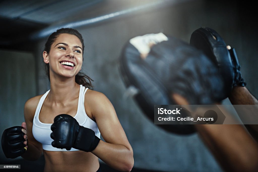 Boxing her way to a ripper body Shot of a young woman sparring with a boxing partner at the gym Boxing - Sport Stock Photo