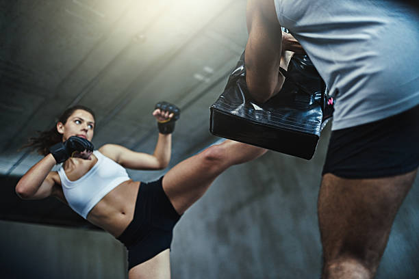 Be prepared for whatever life throws at you Shot of a young woman sparring with a boxing partner at the gym kickboxing photos stock pictures, royalty-free photos & images