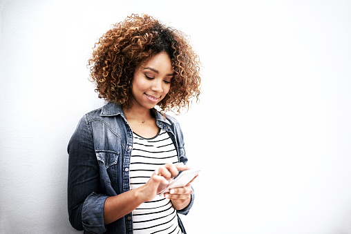 Cropped shot of a young woman using her cellphone against a white background