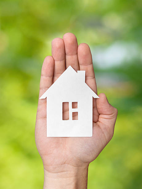 istock Hand holding white paper house figure on green background 618983502