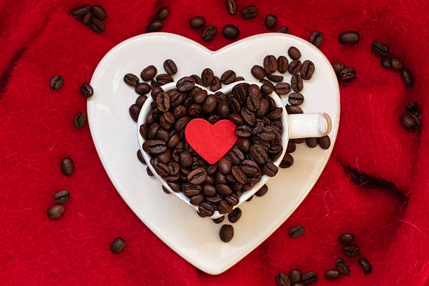 istock Heart shaped cup with coffee beans on red 619044848