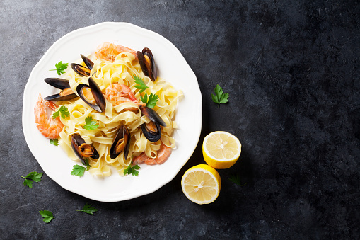 Pasta with seafood on stone table. Mussels and prawns. Top view with copy space