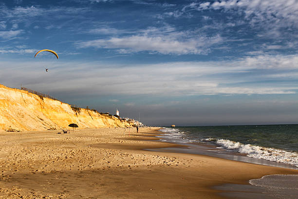 Huelva, Spain - October 8, 2016: Man paragliding over Matalascanas sandy beach before sunset