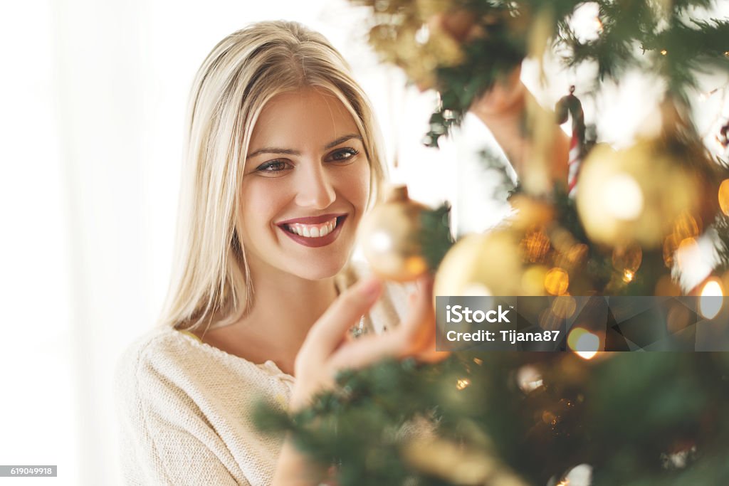 Beautiful, young woman decorating a Christmas tree Women Stock Photo