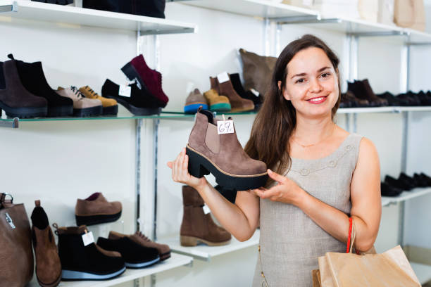 istock Young woman choosing fall boots in shoes store 619051398