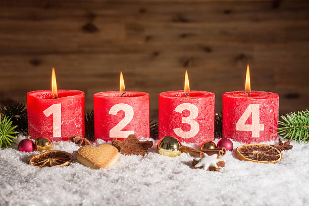 quattro candele dell'avvento accese nella neve - advent calendar christmas number red foto e immagini stock