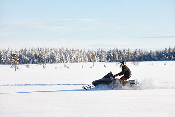 Man driving snowmobile in Finland Man driving sports snowmobile in Finnish Lapland in a sunny day finnish lapland stock pictures, royalty-free photos & images