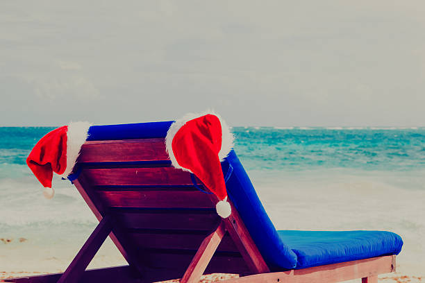 istock chair lounge with red Santa hats on tropical beach 619053192