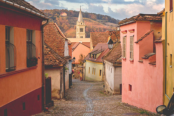 stein gepflasterte alte straßen mit bunten häusern in sighisoara - rumänien stock-fotos und bilder