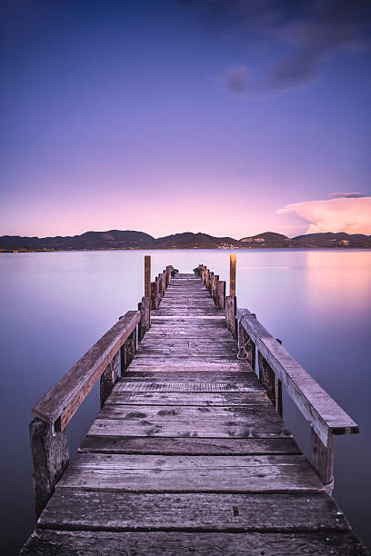istock Wooden pier or jetty on  blue lake sunset sky reflection 619058416