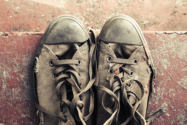 Old sneakers stand on red concrete stairs, closeup photo, top view. Retro stylized photo with tonal correction filter effect