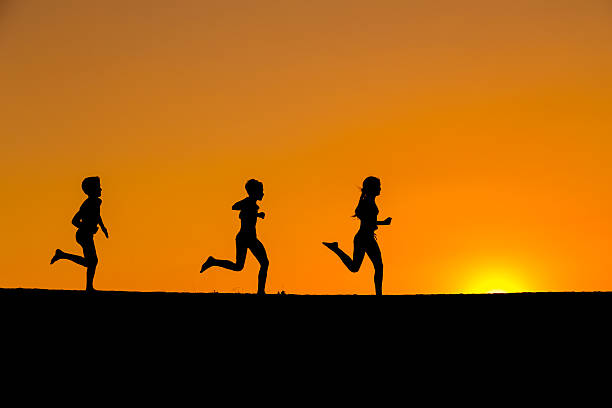 istock silhouette of running kids against sunset 619064676
