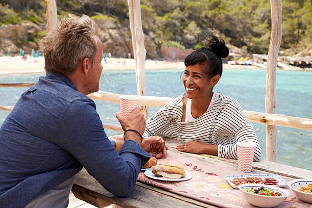 istock Middle aged couple at table by the sea looking at 619068100