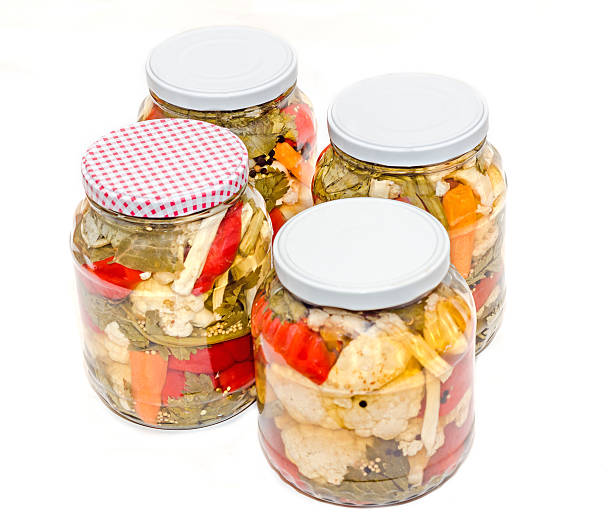 Jars with pickles containing cauliflower, cucumber, red pepper