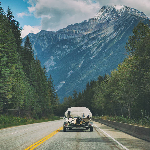 Car towing boat through the mountains in the Canadian Rockies of Yoho National Park, British Columbia, Canada.